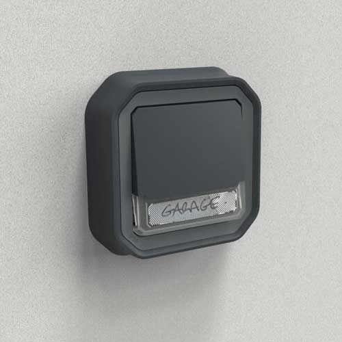 Poussoir anthracite étanche IP55 Legrand Plexo avec porte-étiquette lumineux pose encastrée contre mur gris