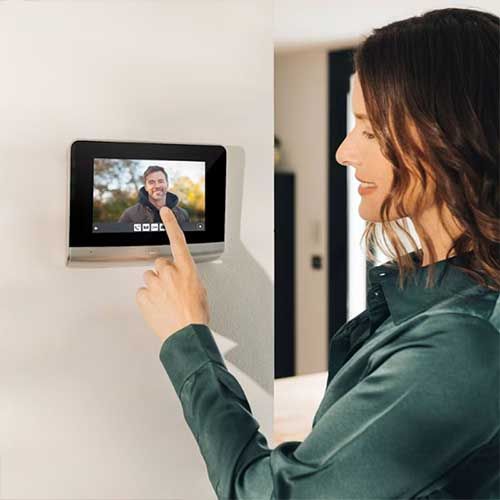 Photo ambiance intérieure avec femme répondant sur le visiophone connecté Somfy et son écran tactile couleur 7