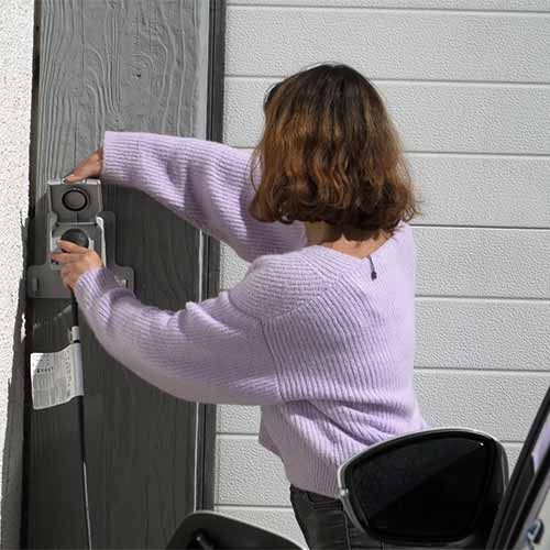 Photo d'une jeune femme branchant son véhicule électrique à la prise LEGRAND Green'up
